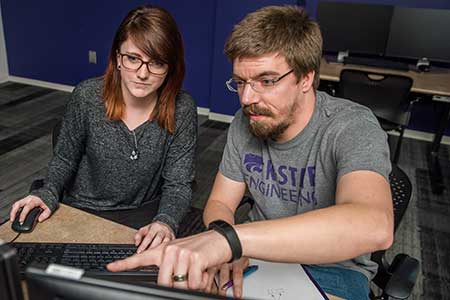 Two students work at a computer.